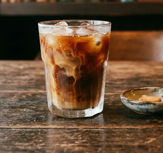 A glass of iced coffee on a wooden table.